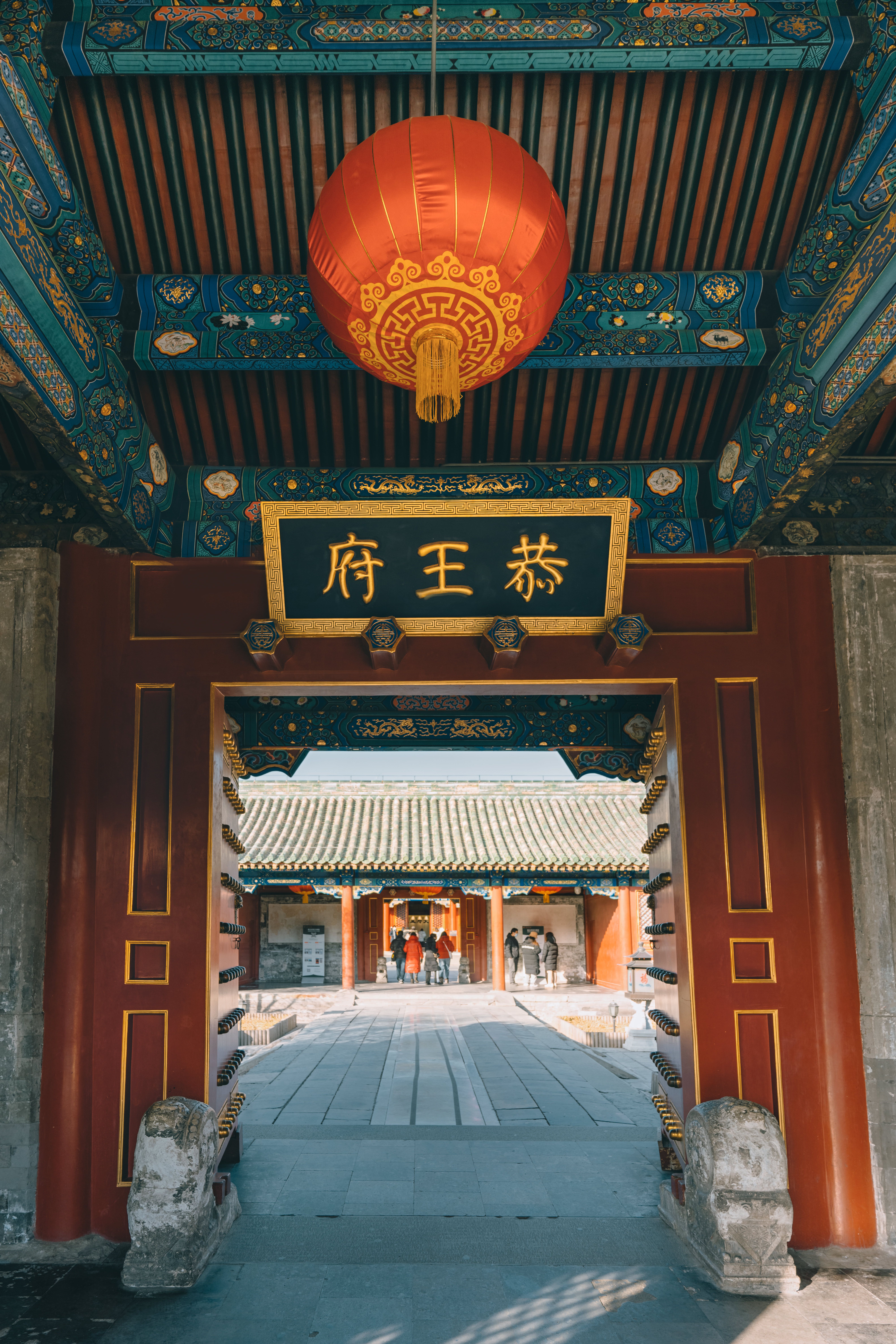 A traditional Chinese temple entrance in Beijing adorned with a red lantern, showcasing intricate architecture.