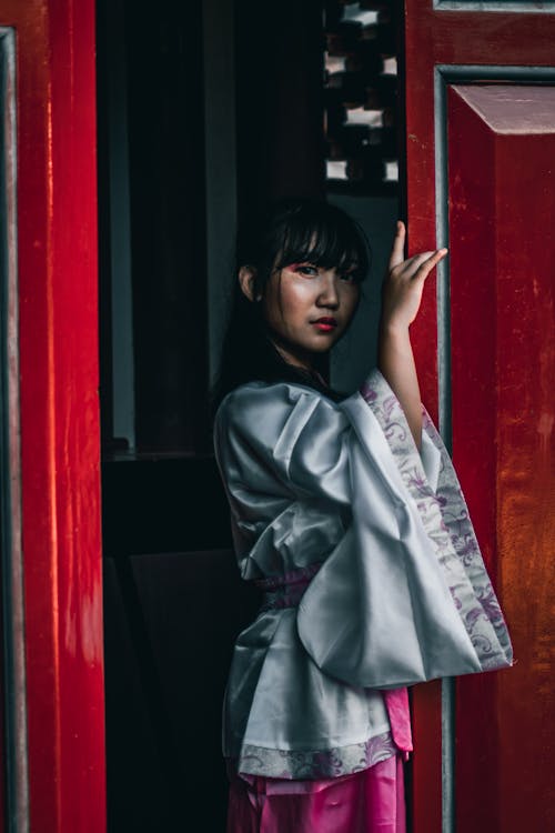 A Woman in Traditional Clothes Standing Beside the Door