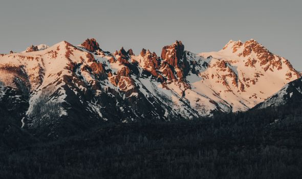 Beautiful snow-capped mountains during golden hour, highlighting picturesque rocky peaks.