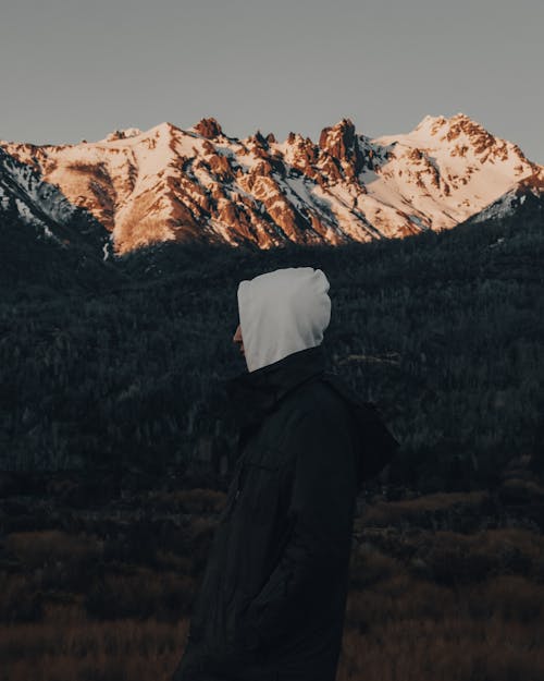 Person in Black Jacket and White Hoodie near Snow Covered Mountains 
