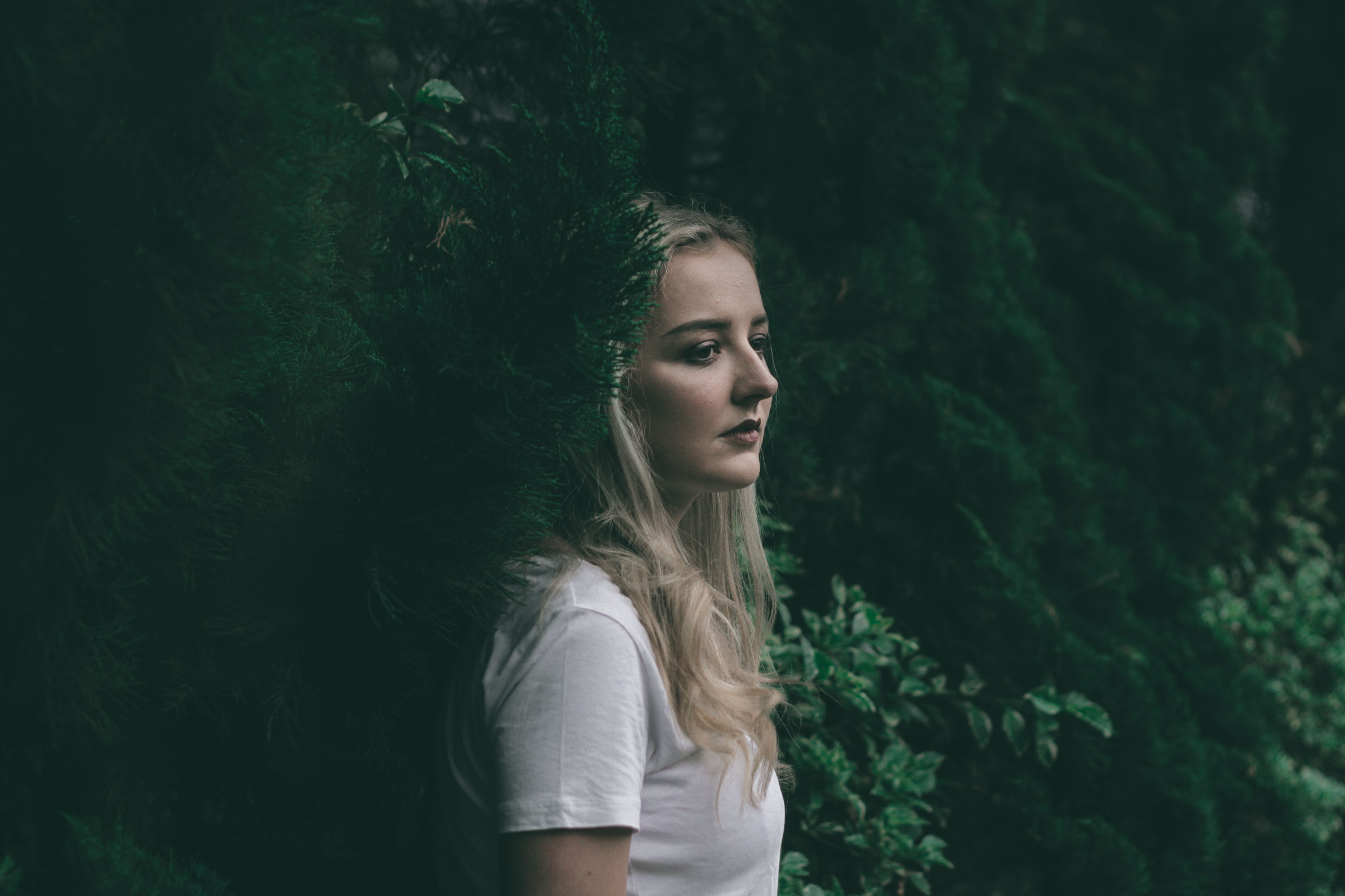 A Woman in White Shirt Standing Near Green Plants · Free Stock Photo