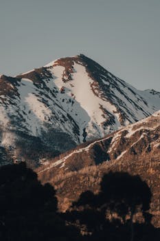 Scenic view of a snow-capped mountain amidst a tranquil natural landscape during daytime.