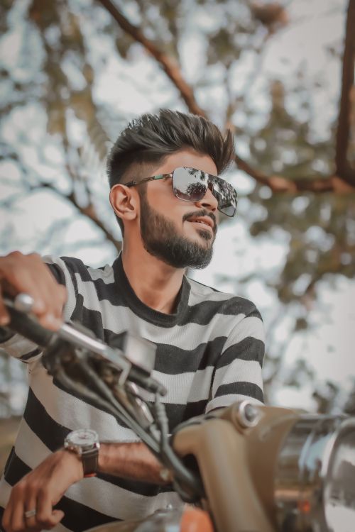 Free Stylish adult man with sunglasses riding a bike outdoors on a sunny day. Stock Photo