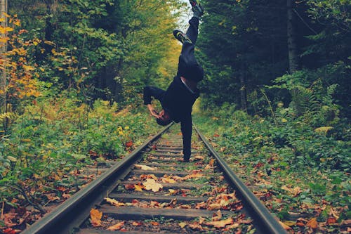 Man Standing With His Right Hand on the Train Rails in Middle of Forest