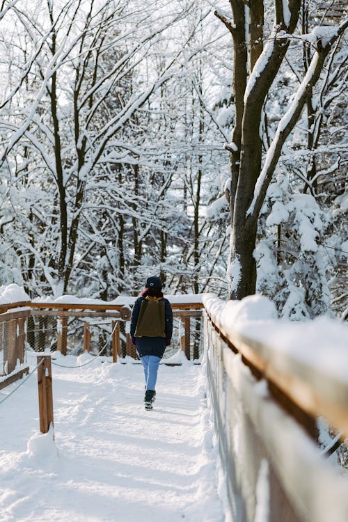 A Woman Walking on Snow Covered Pathway