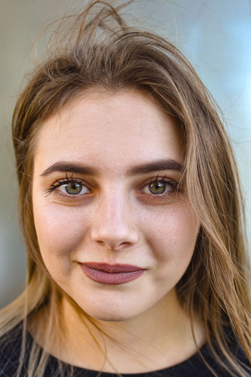 A young woman with a warm smile captured in a close-up portrait, highlighting her expressive eyes.