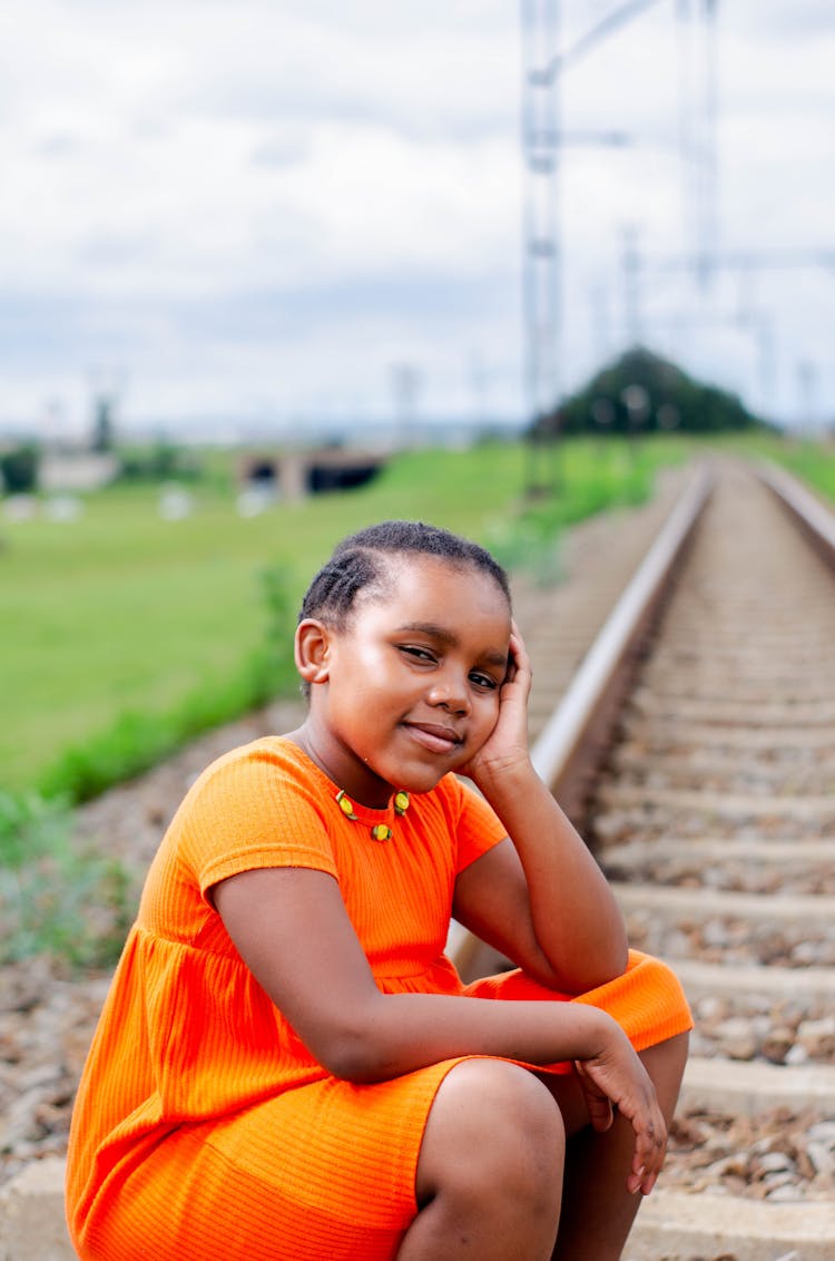 Cute Black Girl In Bright Orange Dress Leaning On Hand