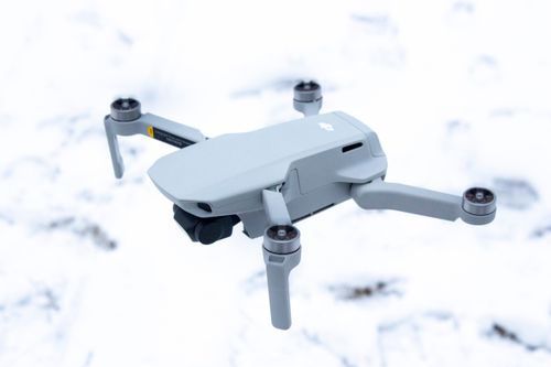 Free A compact drone in flight over a snowy landscape, showcasing its sleek design. Stock Photo