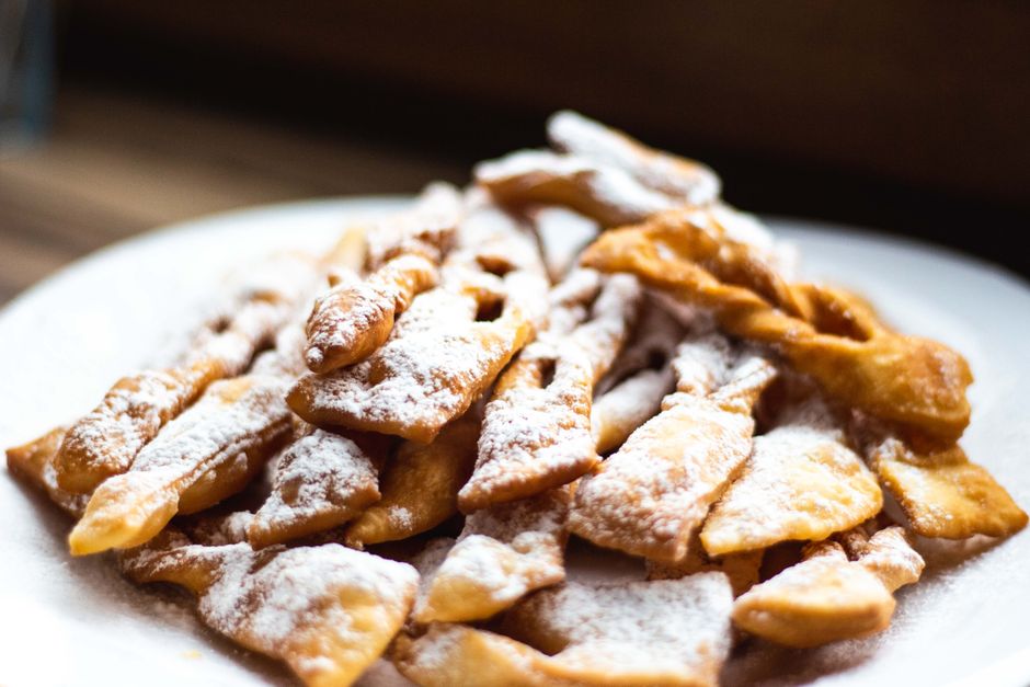 Close-up of traditional Polish faworki pastries dusted with powdered sugar on a plate.