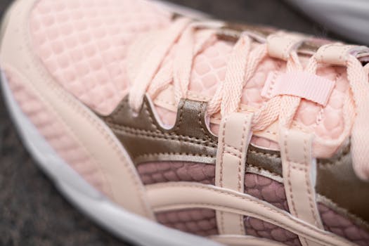 Detailed close-up of a pink sneaker with textured pattern and lace design, showcasing modern footwear style.