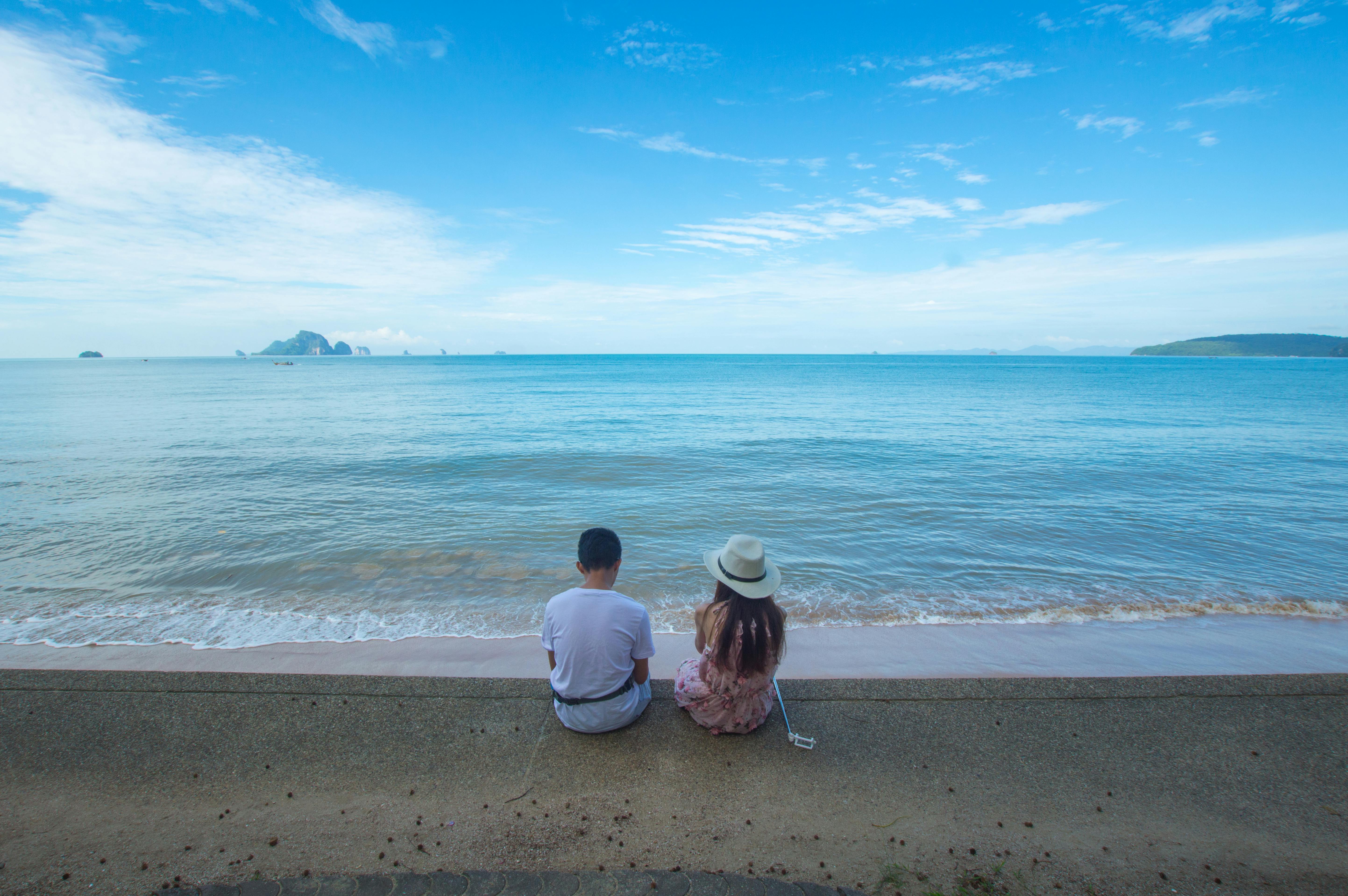 man and woman sitting on seashore