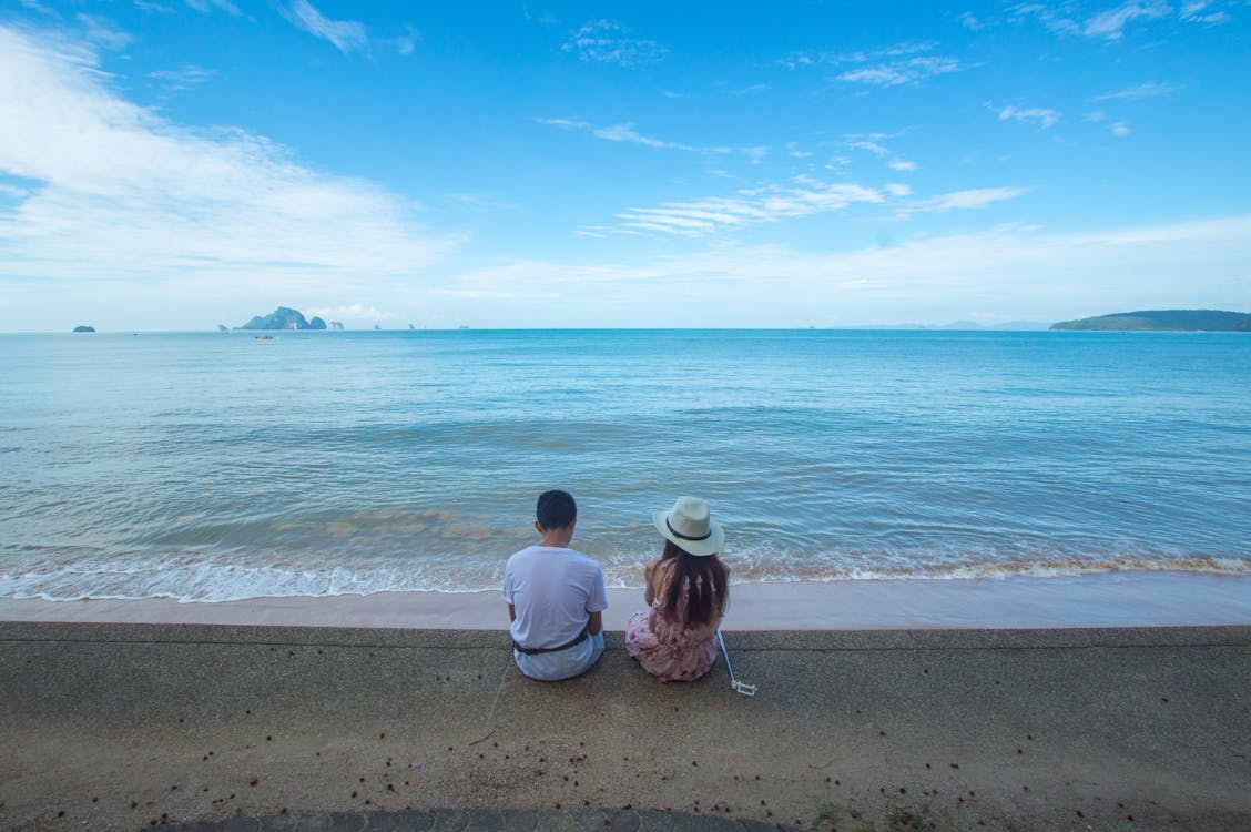 Man and Woman Sitting on Seashore