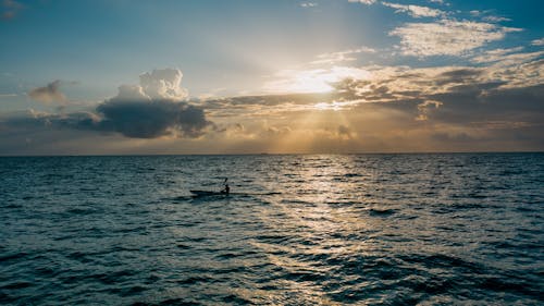 Person kayaking on rippling water of ocean at sunset