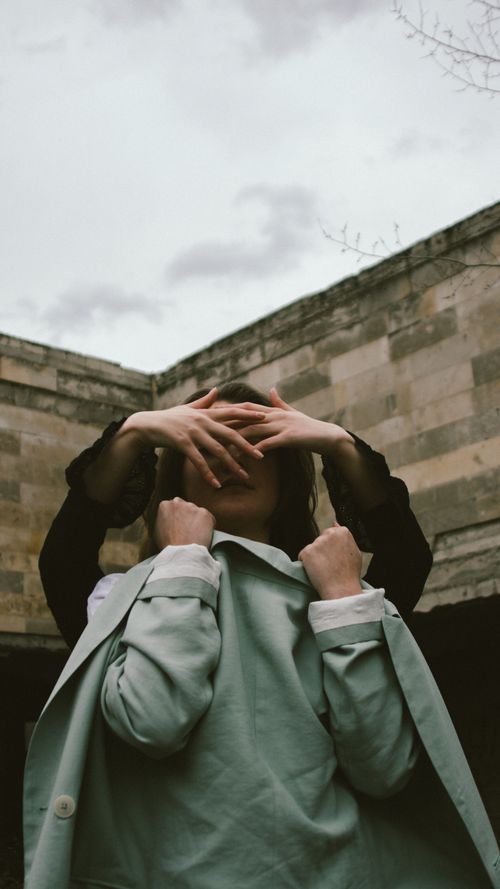Free Artistic shot of a person with face covered by hands, outdoors. Stock Photo