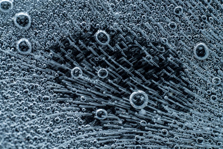 Macro shot of textured black bird plumage with central area free of small bubbles and full of short strokes