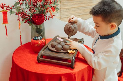 Free A child in traditional attire pouring tea during a cultural ceremony indoors. Stock Photo