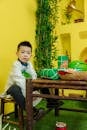 A Boy Sitting at a Wooden Table with Gifts