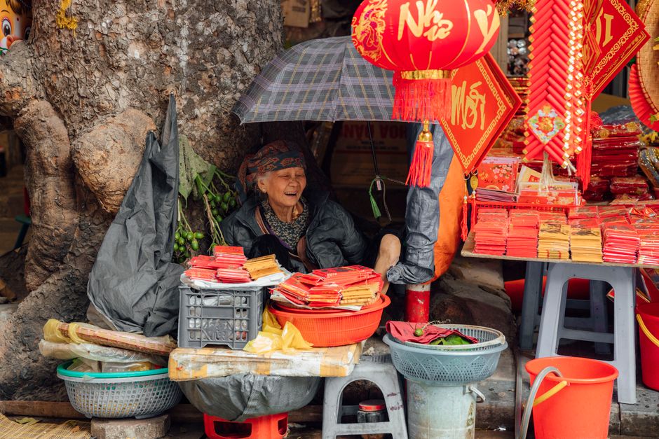 An elderly woman selling vibrant traditional decorations in an outdoor market scene. Perfect for festive themes.