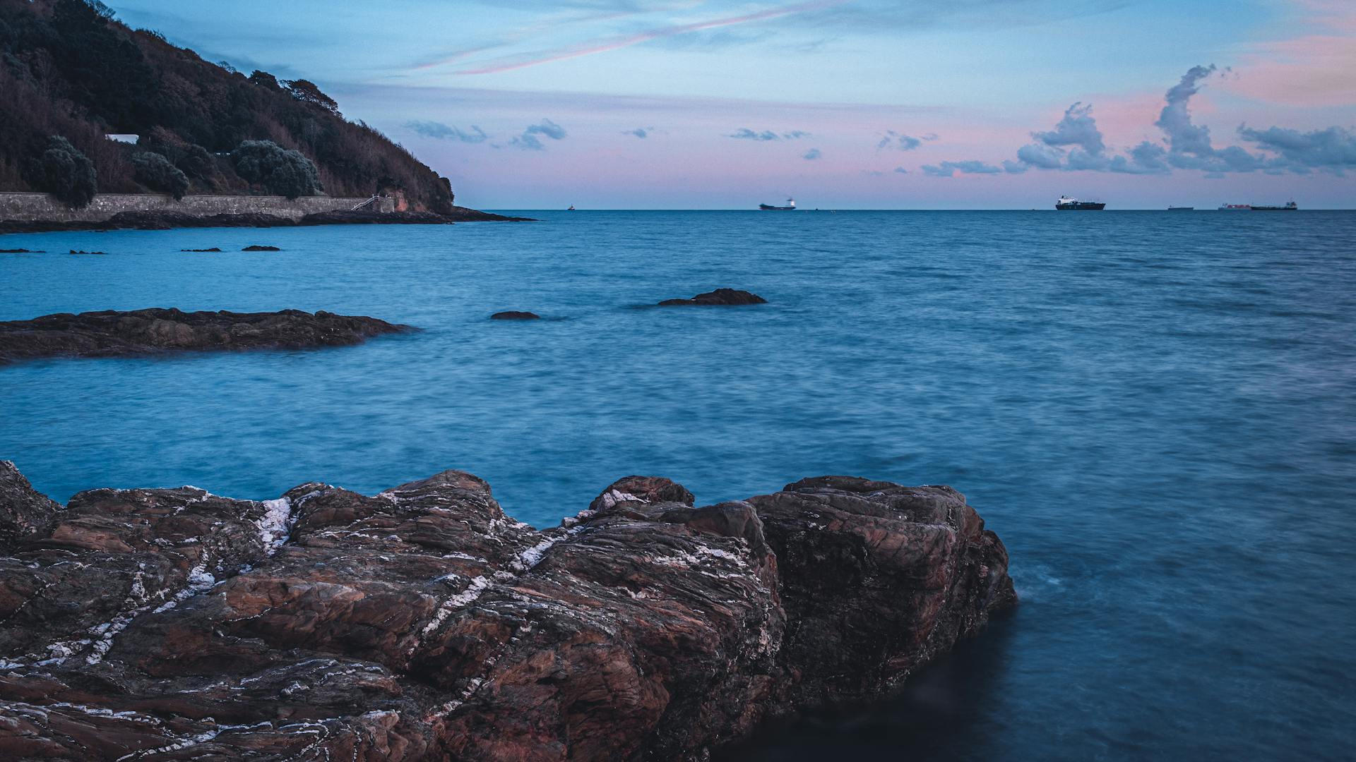 Twilight sky over Falmouth coast with rock formations and ocean waves, creating a tranquil seascape.