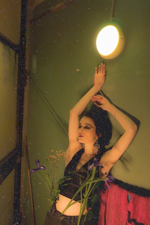 Gentle slender woman with blooming flowers near glowing lamp