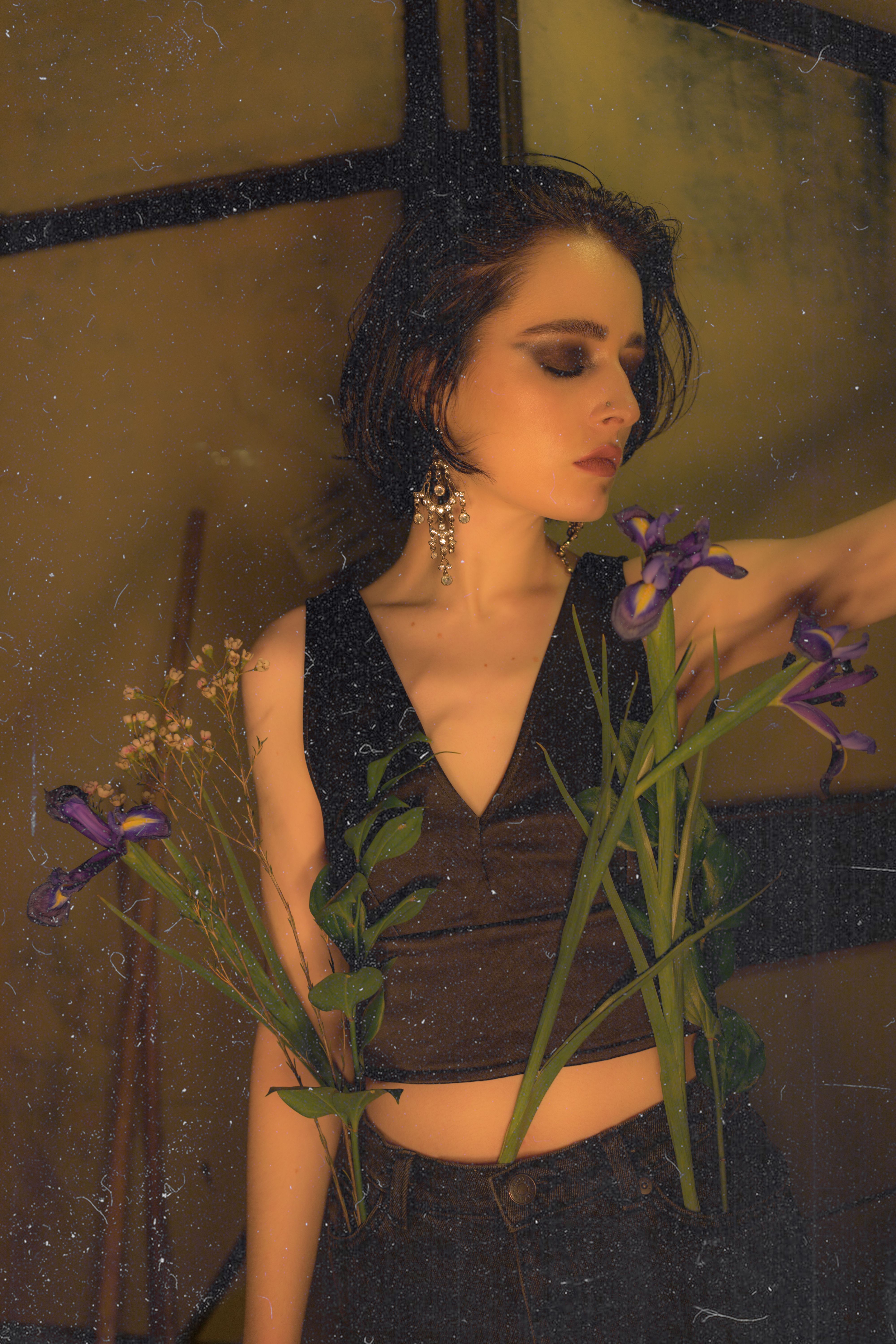 Gorgeous elegant female with short dark hair and eyes closed with flowers in blossom