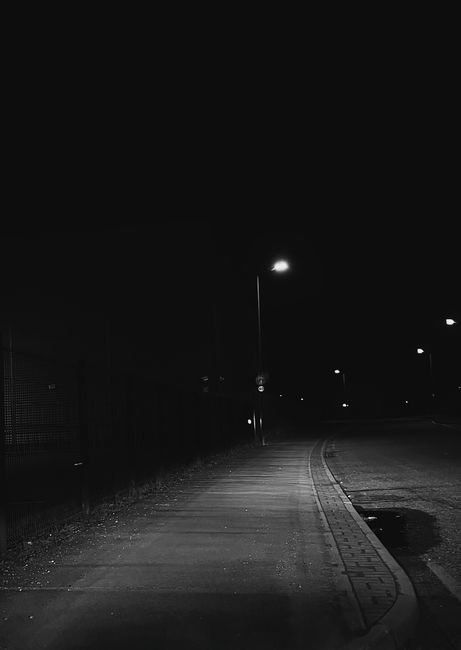 A dark and moody night scene of an empty street in Thatcham, England, illuminated by streetlights.