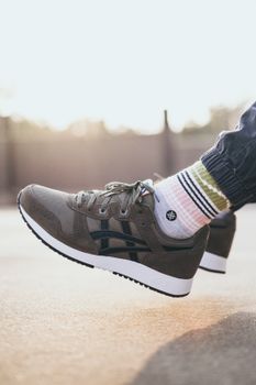 Close-up of a green sneaker and striped socks in sunlight, showcasing fashion style.