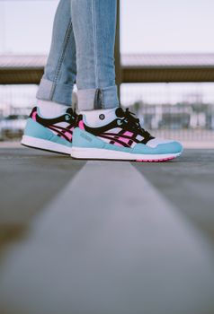Fashionable blue and pink sneakers worn outdoors on an urban street background.