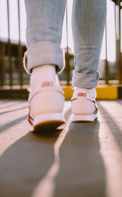 Free Close-up of legs walking in Asics sneakers on a sunny day. Stock Photo