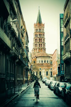 骑自行车的人驶近法国图卢兹圣塞尔宁大教堂的街景