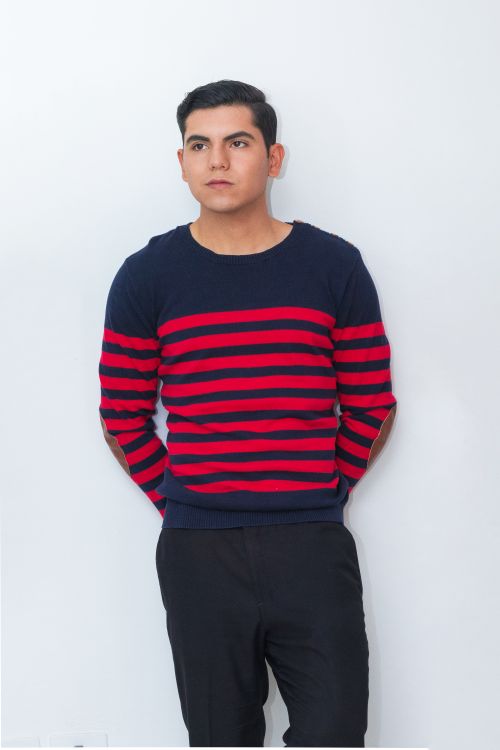 Free Confident young man in a red and blue striped sweater standing against a white backdrop. Stock Photo