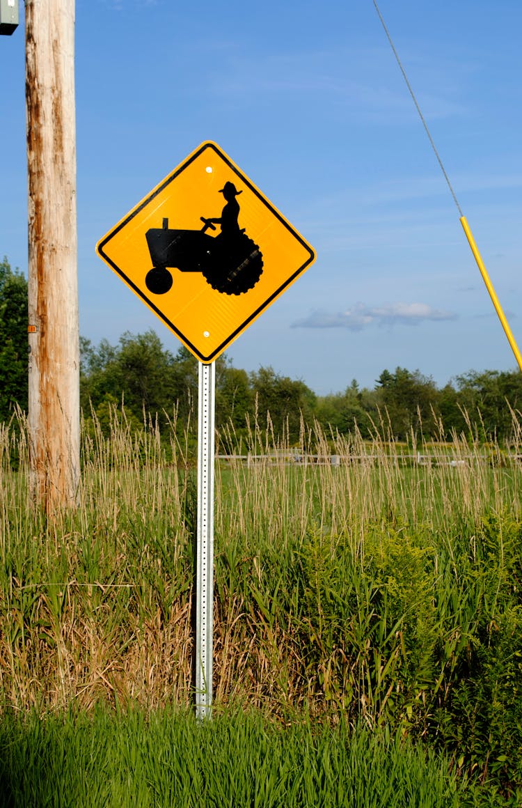 Tractor Ahead Road Sign In Summer Countryside