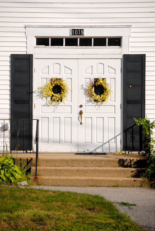 Modern cottage entrance doors decorated with yellow flower wreaths in countryside on sunny weather