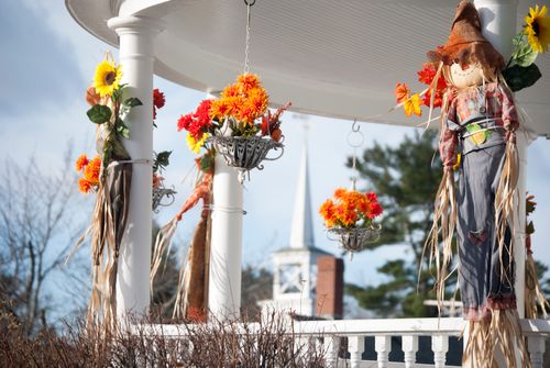 Free Scarecrow toys and bunches of flowers decorating veranda pillars of contemporary cottage in sunny countryside Stock Photo