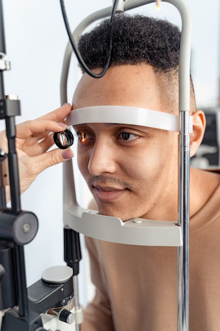 A man undergoing an eye examination with a slit lamp in a clinic setting.