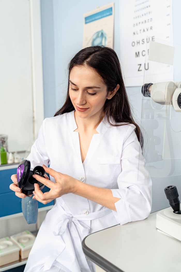 Eye-care professional handling an optical lens during a clinical assessment