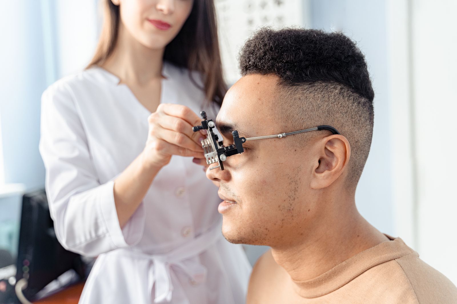 Optometrist fitting a patient with a trial frame during an eye exam