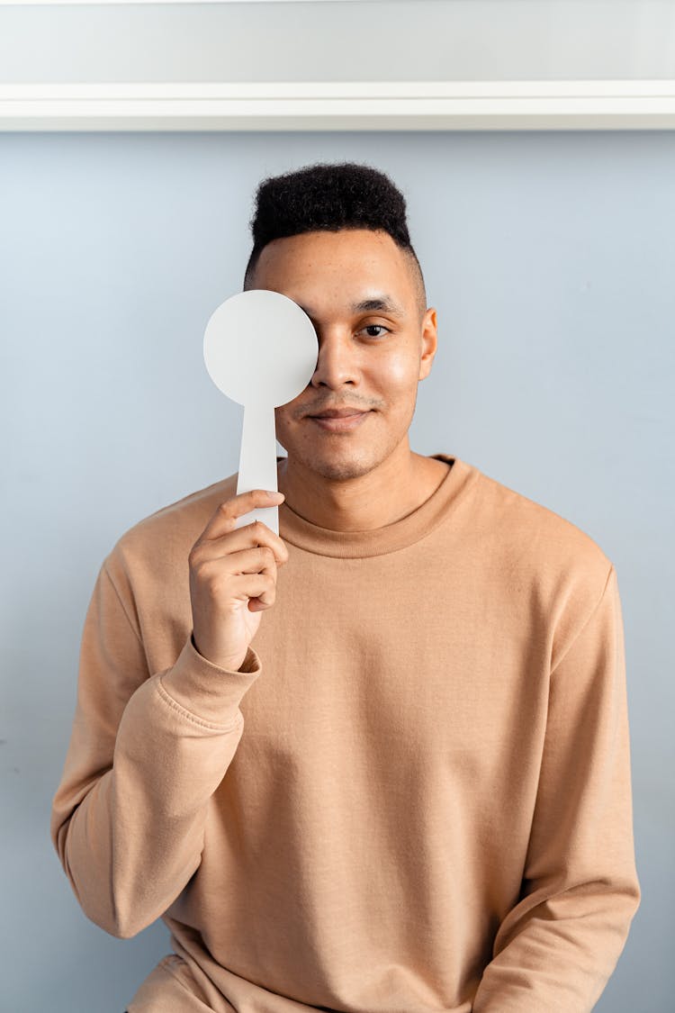 Man In Brown Sweater Covering His Other Eye 