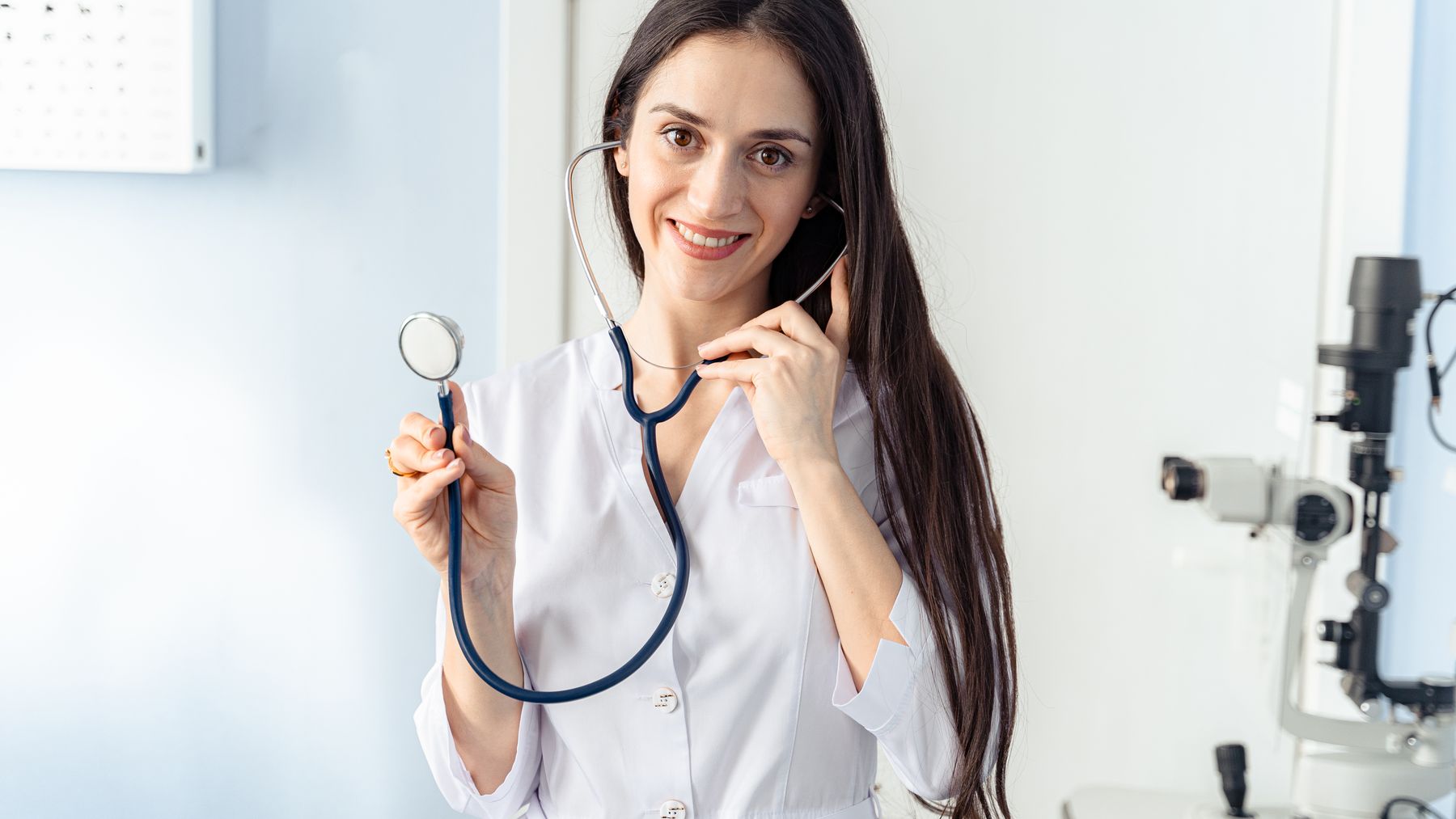 Smiling female physician with stethoscope in a welcoming consultation setting