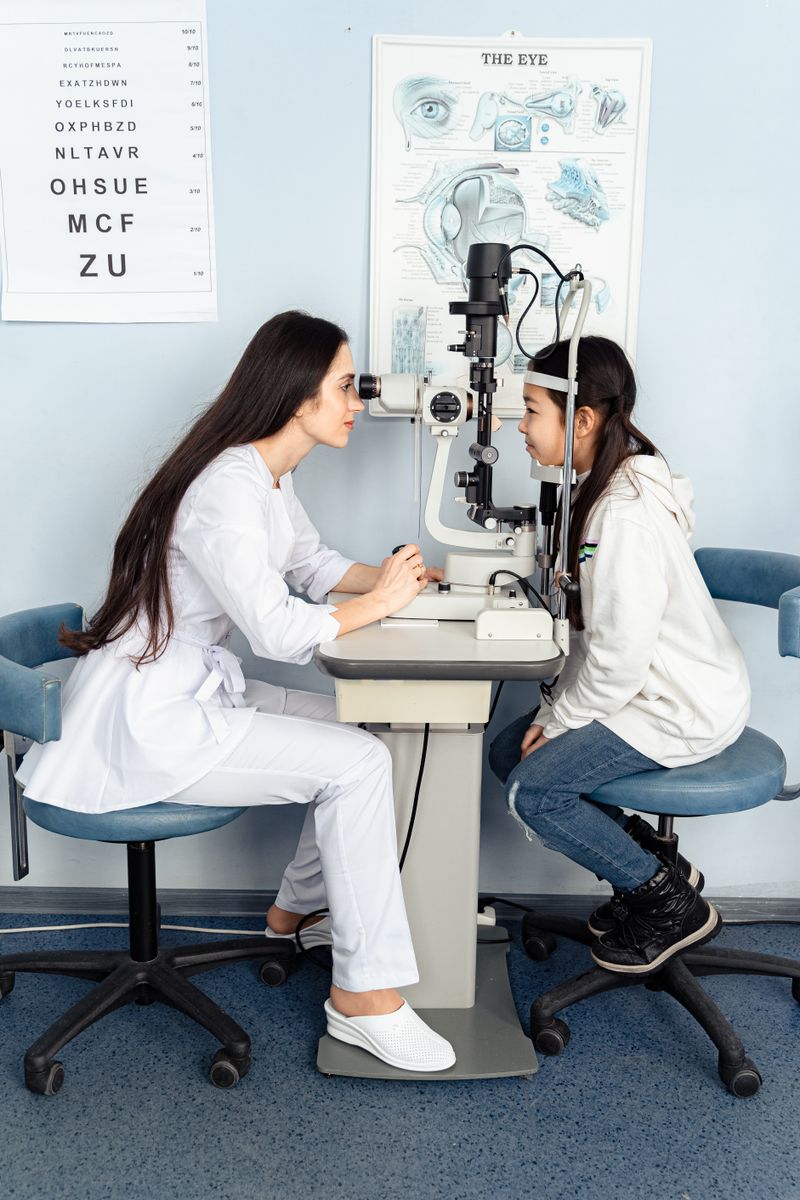 Optometrist examining a young girl with a slit lamp in a bright clinic