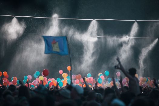 Colorful balloons at a lively festival in Budapest with a crowd celebrating under misty lights.