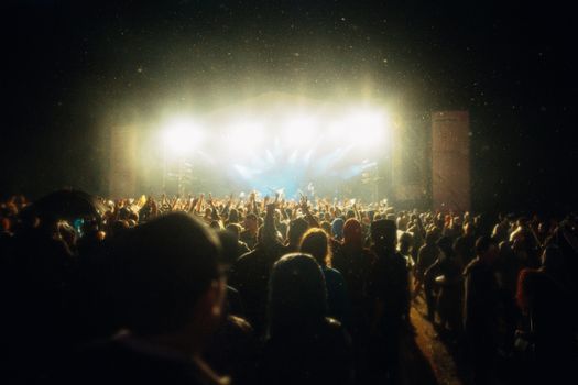 Vibrant evening concert scene at a festival, capturing a lively audience under bright stage lights.
