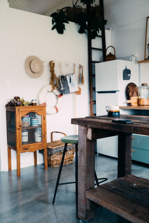 Free A charming rustic kitchen interior featuring a wooden table, ladder shelf, and wall decor. Stock Photo