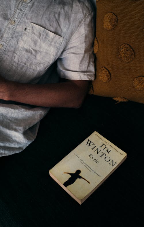 Close-Up Shot of a Person beside a Novel Book