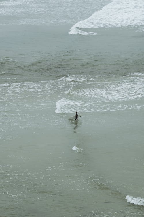 Aerial Shot of a Person Carrying a Surfboard