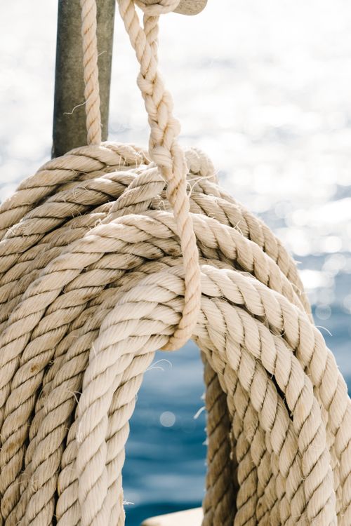 Free Nautical rope looped around a post on a boat with a sparkling sea background. Stock Photo