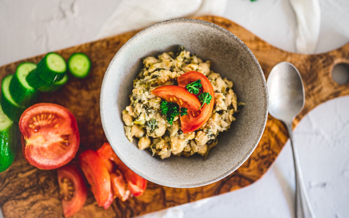 A top view of a nutritious chickpea salad with fresh tomatoes and cucumbers on a wooden board.