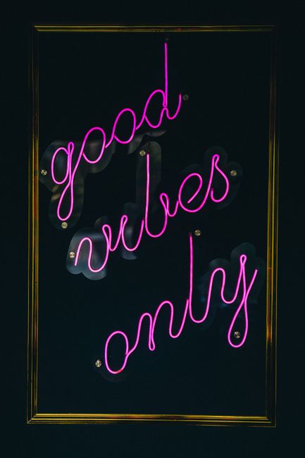 Vibrant neon light sign with 'good vibes only' on a dark background.