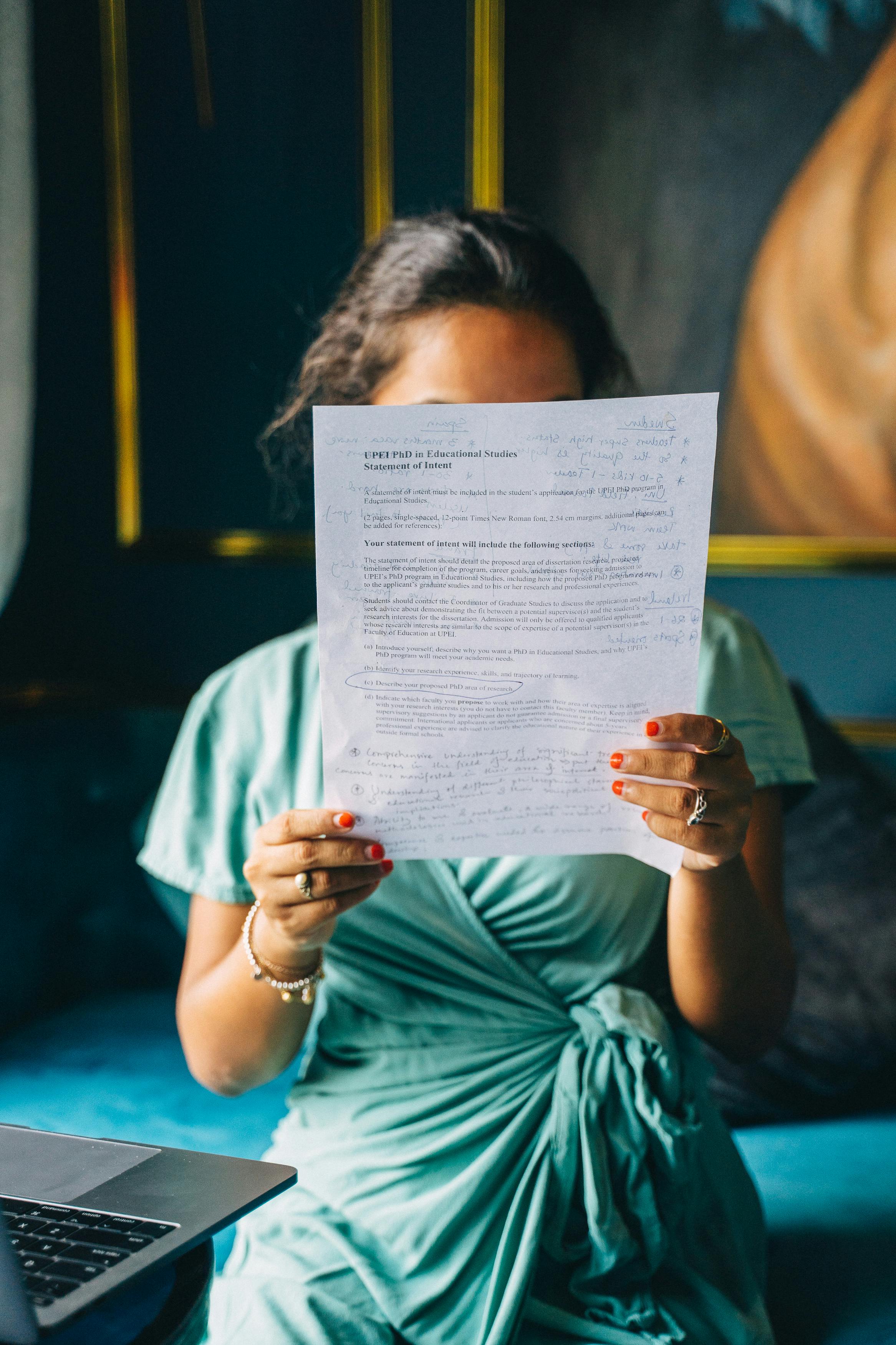 Woman in Teal Shirt Holding White Printer Paper