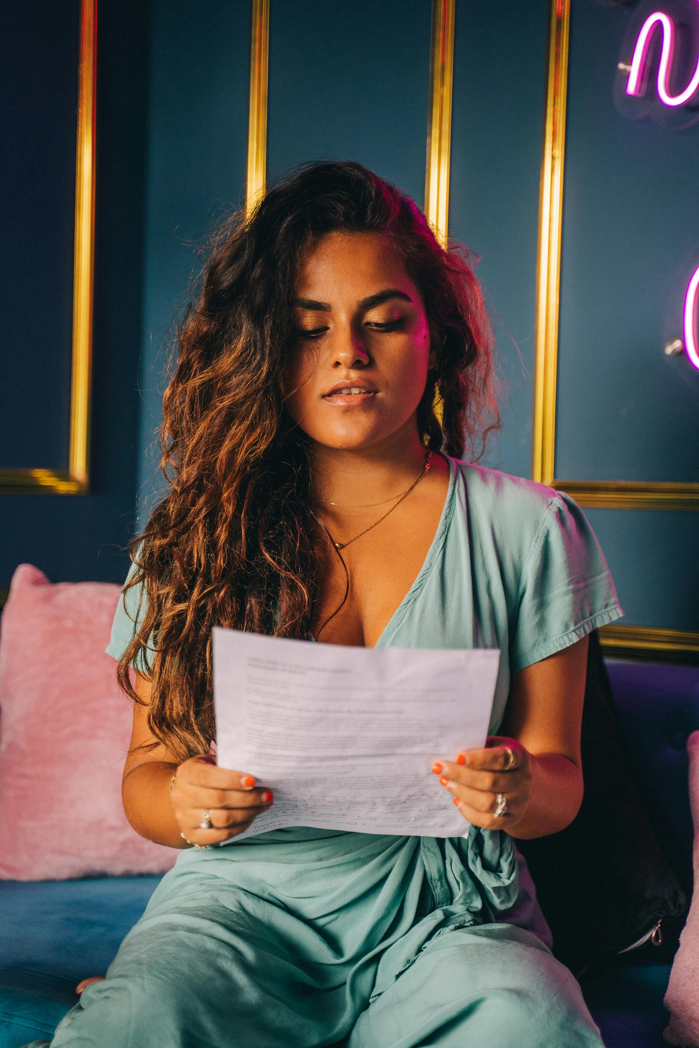 Woman in Teal and White V Neck T-shirt Holding White Printer Paper
